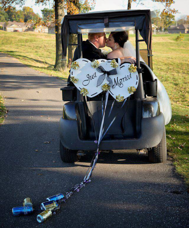 Wedding couple kissing in golf cart with just married sign and cans attached to ribbon.