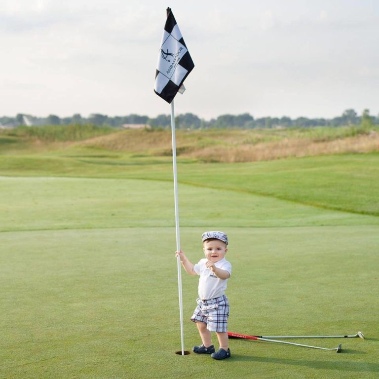 Baby in golf outfit holding the flag